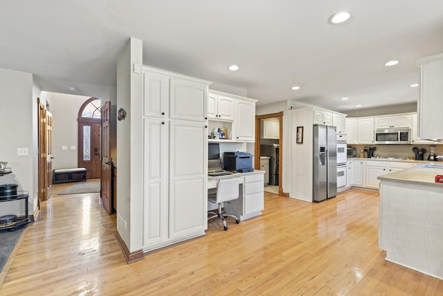 kitchen featuring a kitchen breakfast bar, white cabinetry, stainless steel appliances, and light hardwood / wood-style flooring