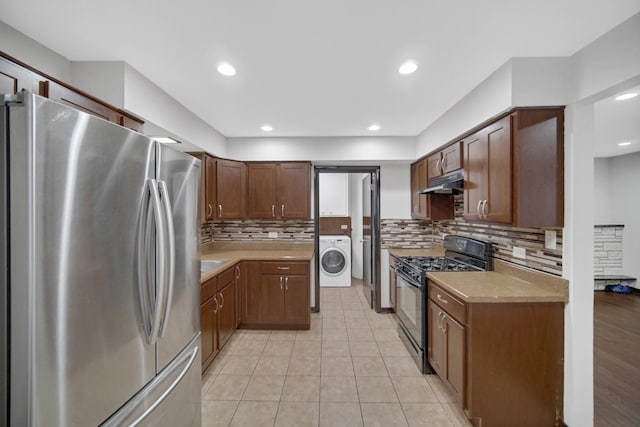 kitchen with gas stove, stainless steel refrigerator, washer / clothes dryer, decorative backsplash, and light tile patterned floors