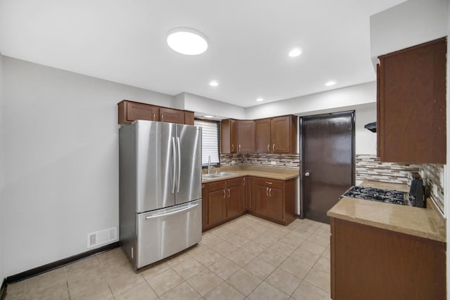 kitchen with decorative backsplash, stainless steel fridge, sink, and stove