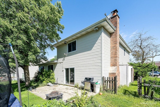 back of property featuring a fire pit, a patio area, and a lawn