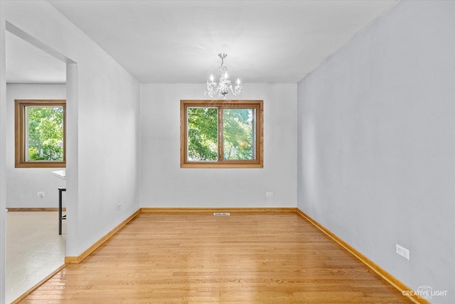 unfurnished room featuring light hardwood / wood-style flooring and a chandelier