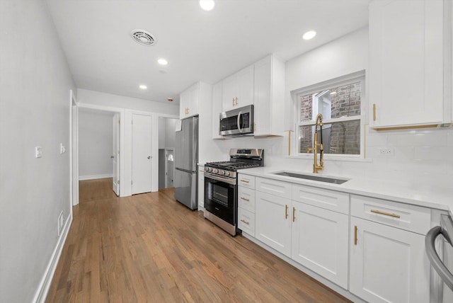 kitchen featuring white cabinets, appliances with stainless steel finishes, light hardwood / wood-style flooring, and sink