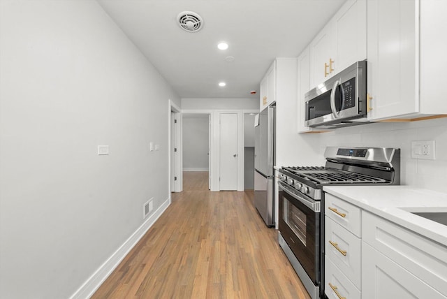 kitchen featuring backsplash, white cabinets, stainless steel appliances, and light wood-type flooring