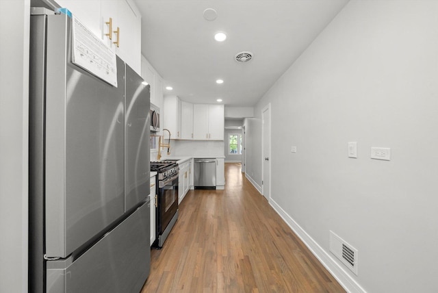 kitchen featuring white cabinetry, sink, stainless steel appliances, backsplash, and hardwood / wood-style floors