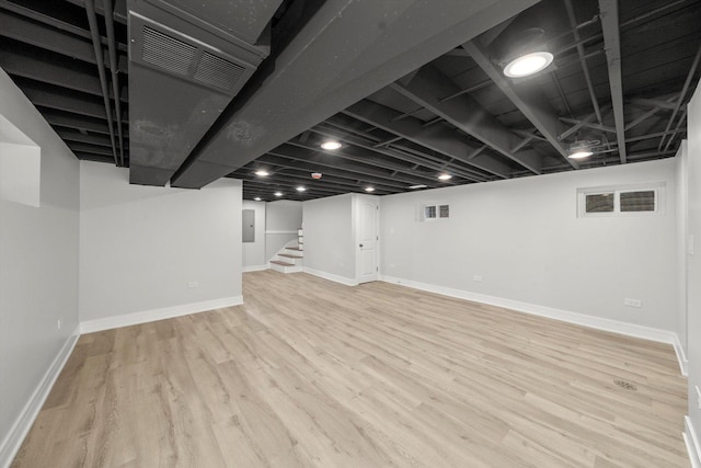 basement featuring electric panel and light hardwood / wood-style floors