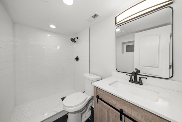 bathroom with vanity, toilet, and tiled shower