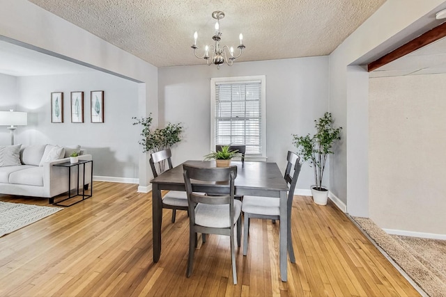 dining room featuring a textured ceiling, an inviting chandelier, and light hardwood / wood-style flooring