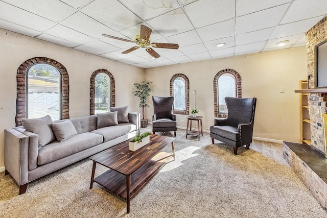 living room with carpet, a paneled ceiling, a large fireplace, and ceiling fan