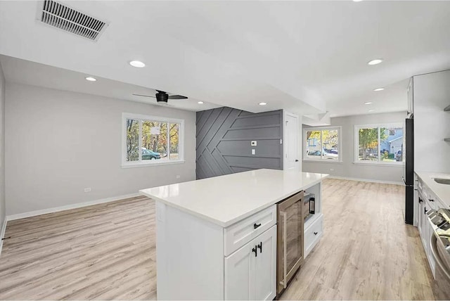 kitchen with a center island, white cabinets, ceiling fan, fridge, and beverage cooler