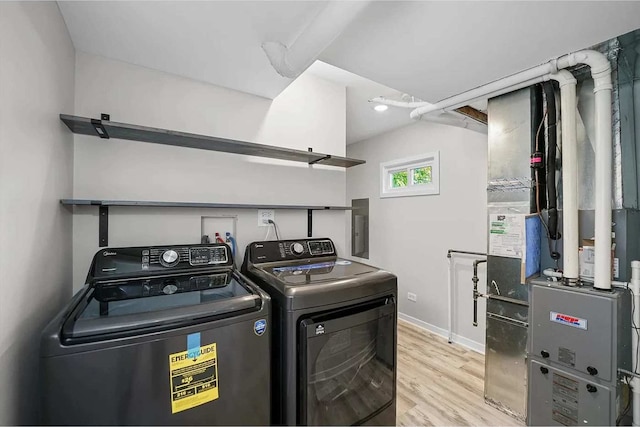 washroom with washer and dryer, electric panel, heating unit, and light hardwood / wood-style floors