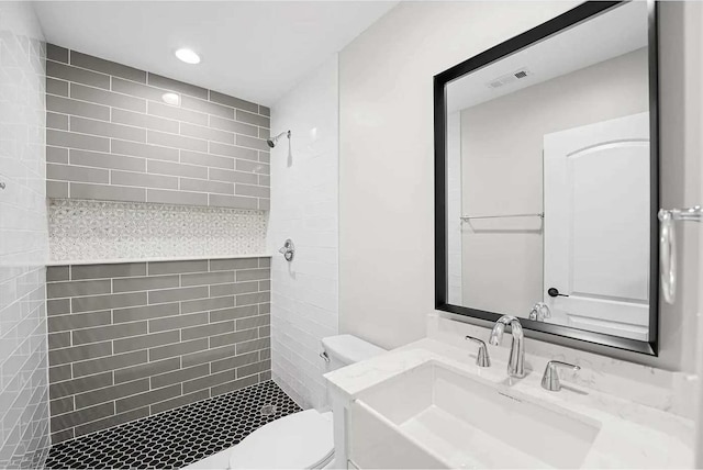 bathroom with vanity, toilet, and a tile shower