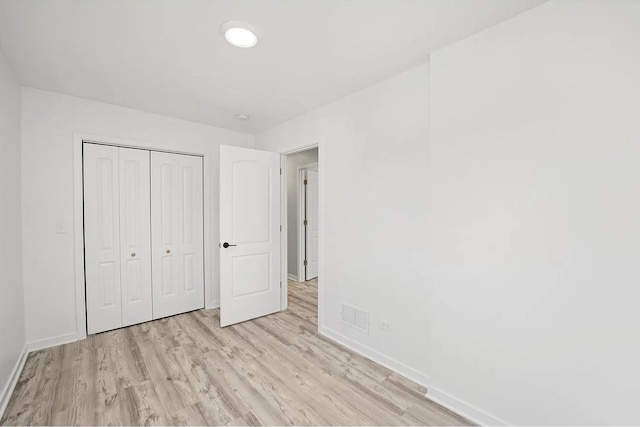 unfurnished bedroom featuring light hardwood / wood-style flooring and a closet