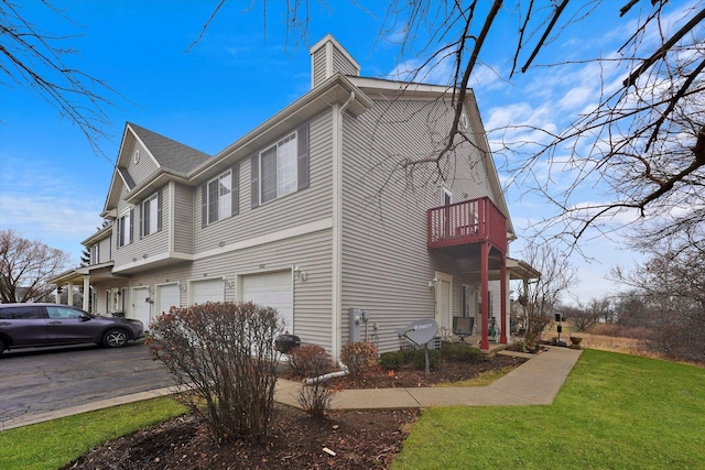 view of home's exterior featuring a garage, a yard, and a balcony