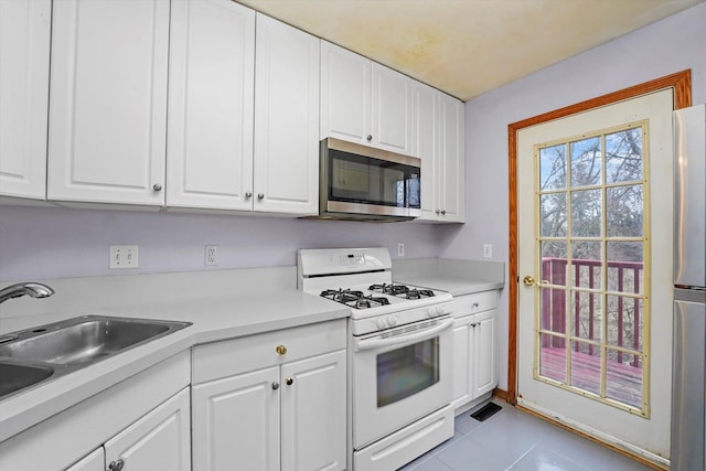 kitchen with white cabinets, light tile patterned floors, sink, and appliances with stainless steel finishes