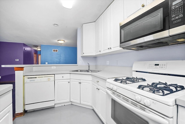 kitchen with light tile patterned flooring, white appliances, white cabinetry, and sink