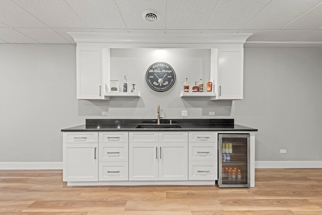 bar featuring white cabinetry, sink, beverage cooler, and light hardwood / wood-style floors