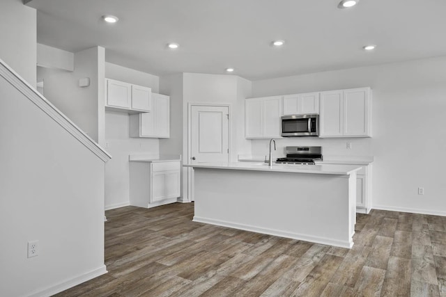 kitchen with sink, stainless steel appliances, an island with sink, light hardwood / wood-style floors, and white cabinets