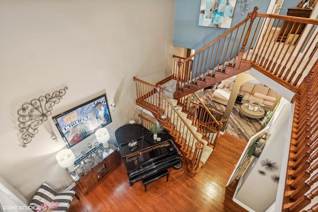 stairway with a towering ceiling and hardwood / wood-style flooring