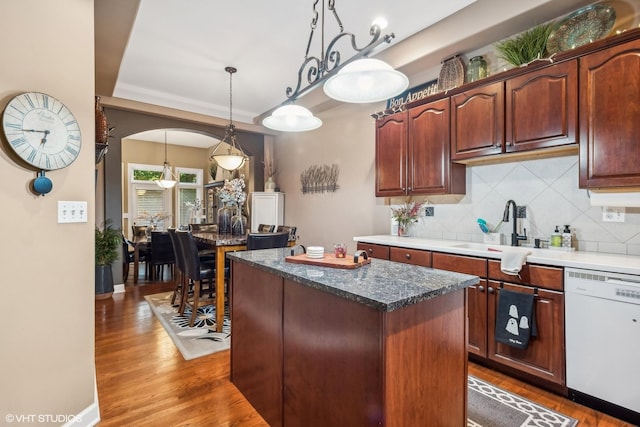 kitchen featuring dark hardwood / wood-style flooring, tasteful backsplash, white dishwasher, pendant lighting, and a center island