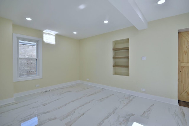 empty room with beamed ceiling and built in features