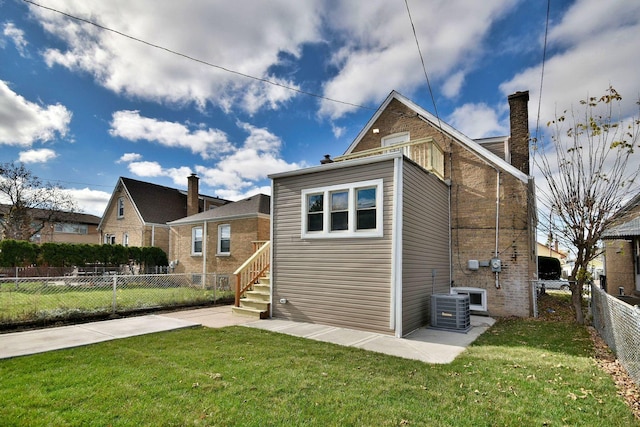 rear view of property with a lawn and central air condition unit