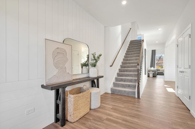 entrance foyer with light wood-type flooring and wooden walls