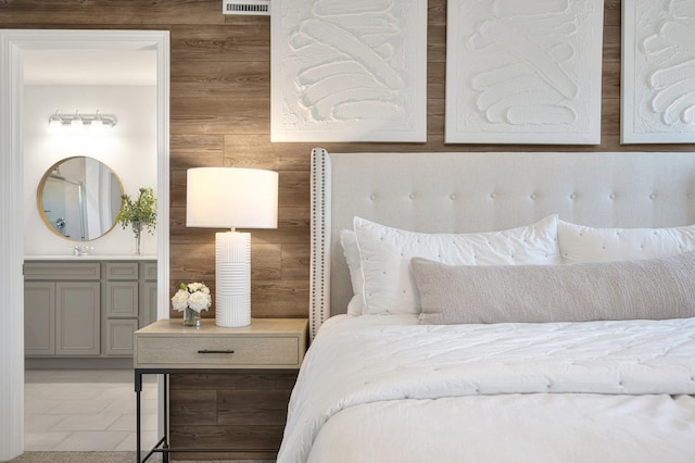 bedroom with sink, wooden walls, and connected bathroom