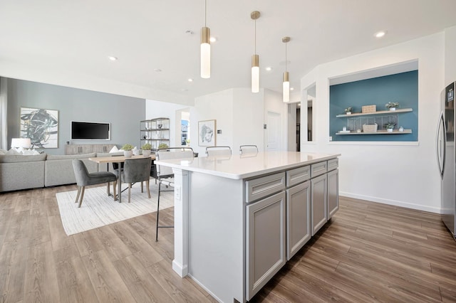 kitchen with light wood-type flooring, a center island, decorative light fixtures, and gray cabinetry