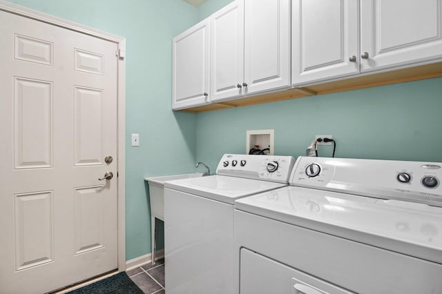 laundry room featuring dark tile patterned floors, washing machine and clothes dryer, and cabinets