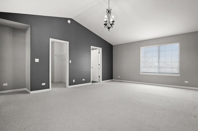 unfurnished bedroom featuring carpet floors, lofted ceiling, a walk in closet, a closet, and a chandelier