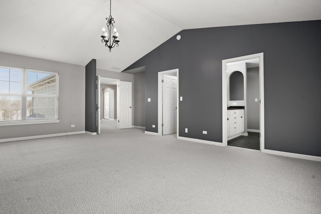 unfurnished bedroom featuring carpet floors, a notable chandelier, connected bathroom, and lofted ceiling