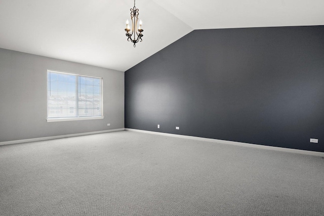 empty room featuring vaulted ceiling, a chandelier, and carpet flooring