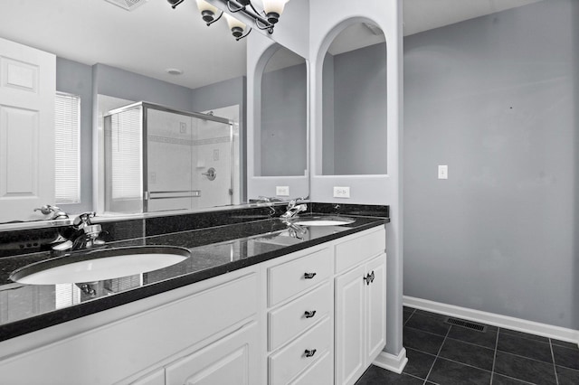 bathroom with a shower with shower door, vanity, and tile patterned flooring