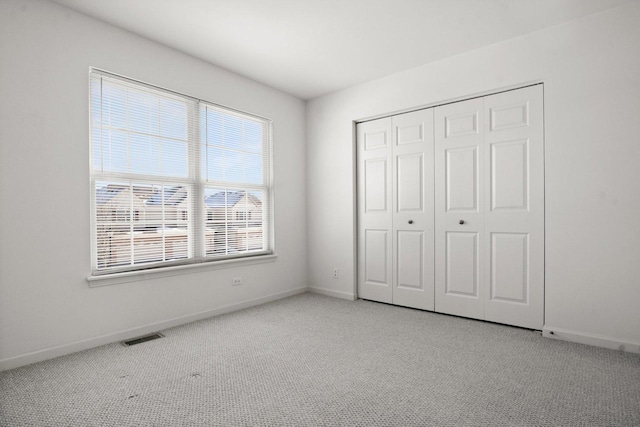 unfurnished bedroom featuring a closet and light carpet