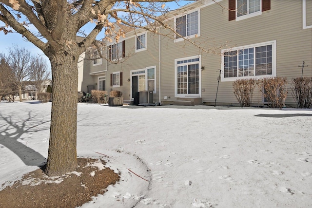 snow covered back of property featuring central AC unit