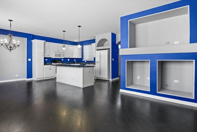 kitchen featuring decorative light fixtures, white cabinets, white appliances, and a kitchen island