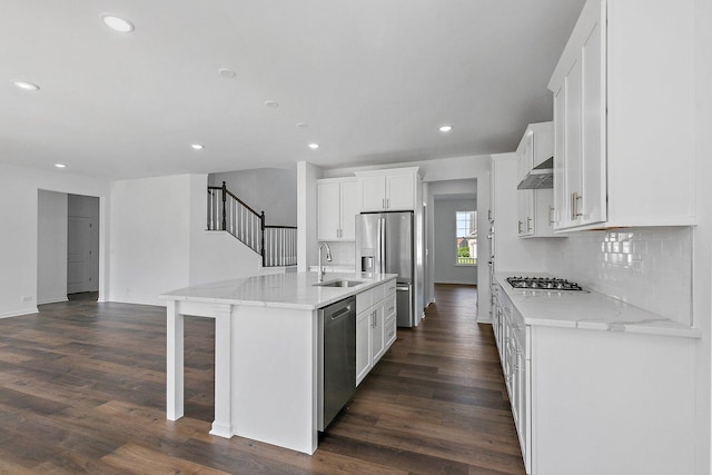 kitchen featuring stainless steel appliances, dark hardwood / wood-style floors, a kitchen island with sink, white cabinets, and exhaust hood