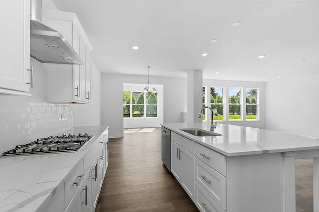 kitchen with a kitchen island with sink, white cabinets, wall chimney range hood, sink, and stainless steel appliances