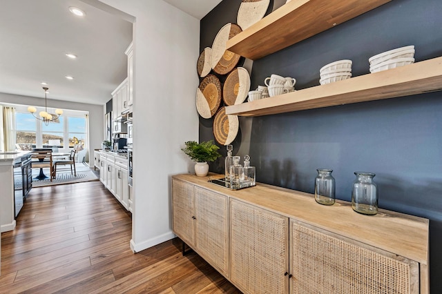 kitchen featuring dark hardwood / wood-style flooring, decorative light fixtures, white cabinetry, and a notable chandelier