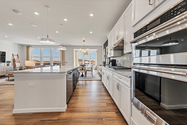 kitchen with decorative backsplash, white cabinets, hanging light fixtures, and appliances with stainless steel finishes