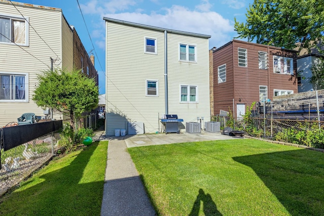 back of house featuring central AC unit, a patio area, and a yard