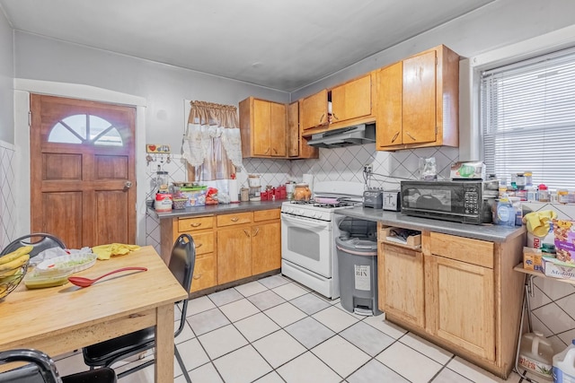 kitchen with decorative backsplash, light tile patterned floors, and white range with gas stovetop