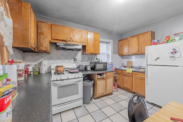 kitchen with light tile patterned floors, white appliances, and backsplash