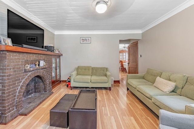 living room featuring light hardwood / wood-style floors, a brick fireplace, and crown molding