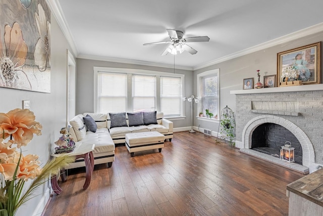 living room featuring ceiling fan, dark hardwood / wood-style floors, ornamental molding, and a brick fireplace