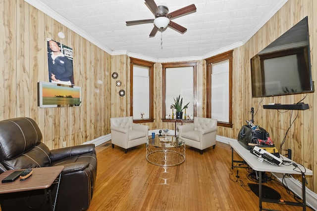 living room featuring hardwood / wood-style flooring, wooden walls, ceiling fan, and ornamental molding