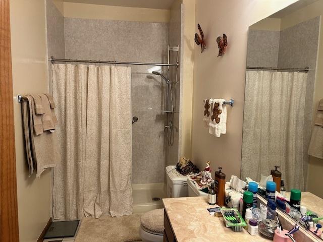 bathroom with vanity, curtained shower, tile patterned floors, and toilet