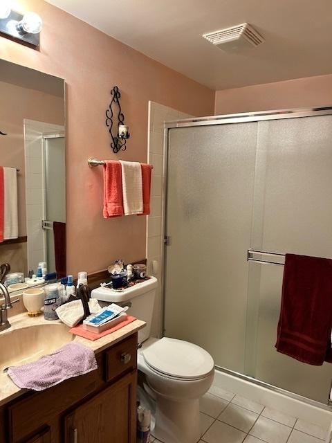 bathroom with tile patterned flooring, vanity, toilet, and walk in shower