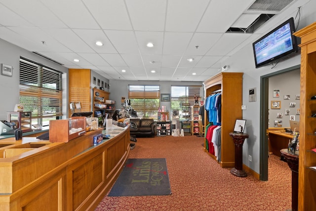 office with a drop ceiling, a healthy amount of sunlight, and carpet flooring