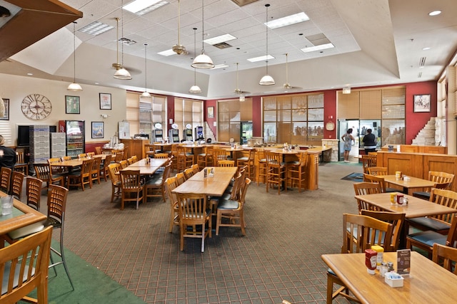 carpeted dining space with a raised ceiling, a towering ceiling, and a drop ceiling